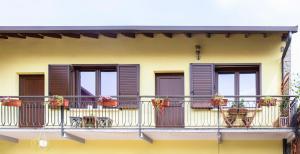 un balcón de una casa con macetas de flores y ventanas en B&B La Corte della Nonna, en Samarate