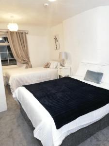 two beds in a bedroom with a black blanket at Ardhill House B&B The Diamond, in the Heart of Ardara Town , F94 C7X9 in Ardara