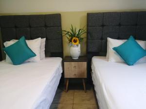 two beds in a room with a vase on a table at Hotel Brickell in Lima