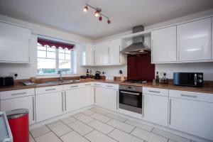 a white kitchen with white cabinets and a window at Wilton Lodge By Horizon Stays in Redcar