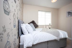 a bedroom with a bed with white sheets and a window at Wilton Lodge By Horizon Stays in Redcar