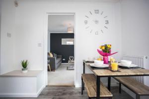 a dining room with a table and a clock on the wall at Hebburn House By Horizon Stays in Stockton-on-Tees