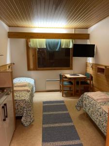 a room with two beds and a table and a television at Luppoloma & Vahtamaja in Saariselka