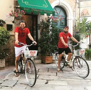 dos hombres montando sus bicicletas con canastas encima en B&B Liu' Palazzo Ducale, en Lesina