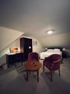 a hotel room with a bed and two chairs and a table at Clifton House Brighton in Portslade