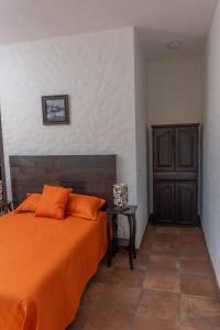 una camera con un letto arancione e un tavolo di Hostal Maria Tepozteca a Tepoztlán