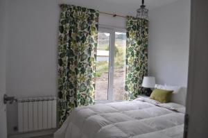 a bedroom with a bed and a window with curtains at Patagonia Hikes Aparts in El Chalten