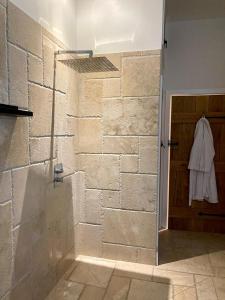 a bathroom with a walk in shower next to a stone wall at Walnut Tree Cottage Barn in Toppesfield