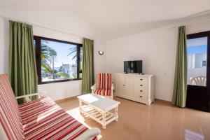 sala de estar con 2 sillas y TV en Apartamentos Flamingo, en Puerto del Carmen