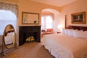 a bedroom with a bed and a fireplace and a mirror at Middlebury Inn in Middlebury