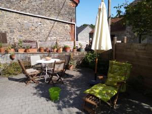un patio con tavolo, ombrellone e sedie di Le petit gîte de Maurenne a Hastière-Lavaux
