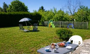 - une table dans une cour avec un parasol et une aire de jeux dans l'établissement La Garçonnière, à Treigny