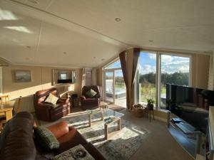 sala de estar con sofás y TV grande en Hot Tub Lodge with Panoramic Views & Free Golf, en Swarland