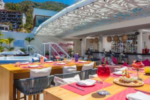
a dining area with tables, chairs, and umbrellas at Almar Resort Luxury LGBT Beach Front Experience in Puerto Vallarta
