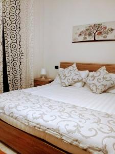 una camera da letto con letto, lenzuola e cuscini bianchi di Sophia' s house appartamento Quartello a Quartu SantʼElena