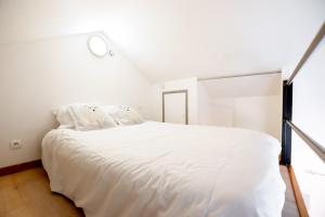 - une chambre avec un lit blanc et une fenêtre dans l'établissement Le Petit Angoumoisin, à Angoulême