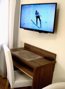 a television hanging on a wall with a table at Apartamenty Jagiellonka in Zakopane