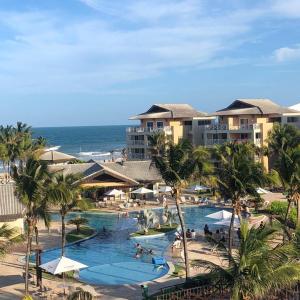 een uitzicht op een zwembad van het resort met palmbomen en de oceaan bij Portamaris Resort Private Apartment 201 in Aquiraz