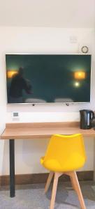 a yellow chair in front of a desk with a television at Bath Road Apartments in Swindon