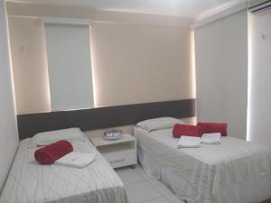 twee bedden in een kamer met rode handdoeken erop bij Portamaris Resort Private Apartment 201 in Aquiraz +29 foto's