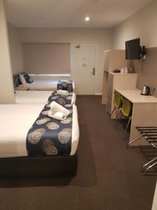 a hotel room with three beds and a desk at Leumeah Lodge in Canberra