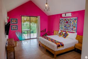um quarto com paredes cor-de-rosa e uma cama num quarto em Hotel y Villas Los Pirules by Rotamundos em Villagrán