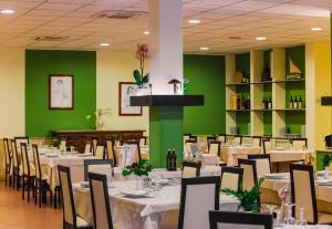 a dining room with tables and chairs and green walls at Hotel Quadrifoglio in Cagliari