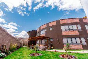 a large brick building with a grass yard at Life Hotel Valle Sagrado in Urubamba