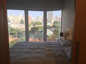 a bed in a bedroom with a large window at FLAT Jardins São Paulo excelente! in Sao Paulo +23 photos