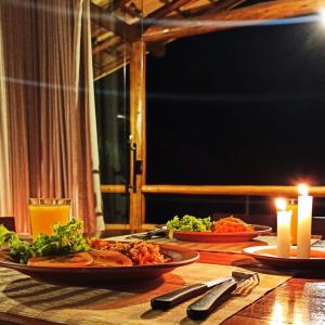 a wooden table with two plates of food and candles at Chalés Beija-flor in Itambé do Mato Dentro +22 photos