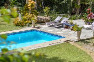 a swimming pool in a yard with two lounge chairs at Pousada Villa Jambo in Petrópolis