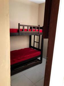 two bunk beds in a room with red sheets at Flat Alicia mar in Tamandaré