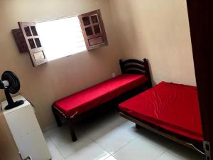 a room with two red beds and a window at Flat Alicia mar in Tamandaré