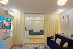 una sala de estar con sofá y una habitación con bañera. en Portami Al Mare - apartament, terasă & curte, en Mamaia Nord – Năvodari