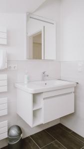 a white bathroom with a sink and a mirror at Traumgarten Haus Leichte Brise in Prerow +17 photos