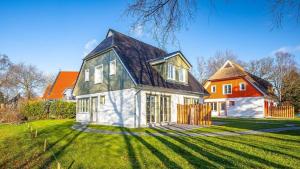 a white house with a black roof on a green yard at Traumgarten Haus Leichte Brise in Prerow