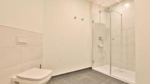 a white bathroom with a shower and a toilet at Strandhaus Zingst Apartment 15 in Zingst +12 photos