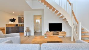 ein Wohnzimmer mit einem Sofa und einem TV in der Unterkunft Strandhaus Zingst Penthouse Seeblick in Zingst