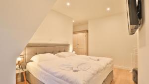 a bedroom with a bed with white sheets and a television at Strandhaus Zingst Apartment 14 in Zingst