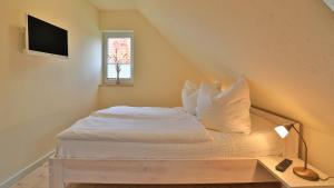 a bedroom with a bed with white sheets and a window at Heideröschen Park Heideröschen 5b in Zingst
