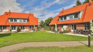 een huis met oranje dak en een groene tuin bij Heideröschen Park Heideröschen 5d in Zingst