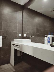 W łazience znajduje się biała umywalka i lustro. w obiekcie ODYSSEY APOLLO BAY w mieście Apollo Bay