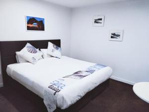 Schlafzimmer mit einem Bett mit weißer Bettwäsche und Kissen in der Unterkunft ODYSSEY APOLLO BAY in Apollo Bay