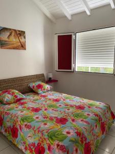 ein Schlafzimmer mit einem großen Bett mit einer Blumenbettdecke in der Unterkunft PARADIS DES SABLES in Les Galets