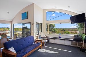 a living room with a blue couch and a large window at Tuhua Views - Waihi Beach Holiday Home in Waihi Beach