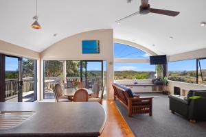 a living room with a table and chairs at Tuhua Views - Waihi Beach Holiday Home in Waihi Beach