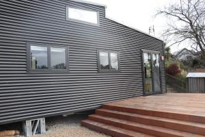 une maison avec deux fenêtres et une terrasse en bois dans l'établissement Big View from a Tiny House, Cashmere, à Christchurch
