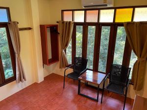 a room with two chairs and a table in front of windows at Art's Riverview Lodge in Khao Sok National Park