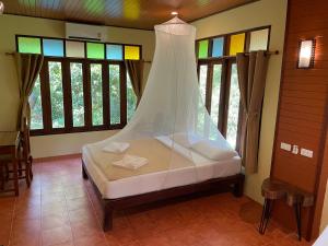 a bed in a room with stained glass windows at Art's Riverview Lodge in Khao Sok National Park