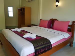 a large bed with pink pillows and towels on it at Discovery House Hotel SHA Plus in Nai Yang Beach